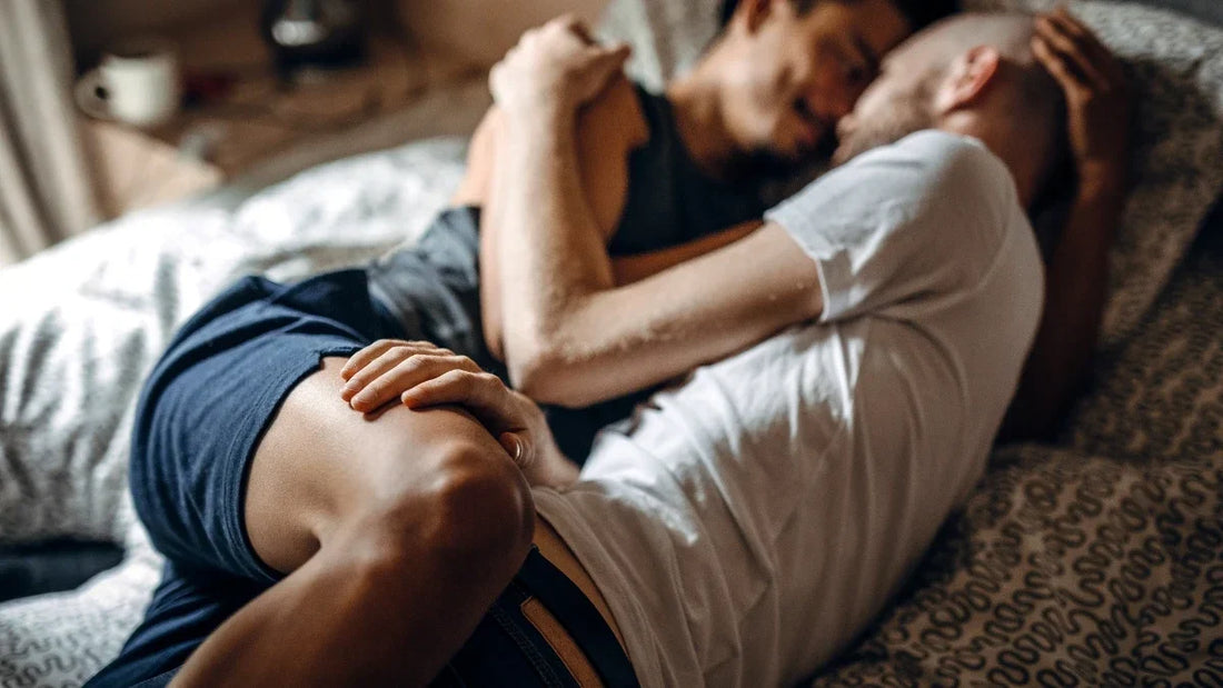 Two men lying together on a bed, relaxed and close — intimacy without the prep anxiety