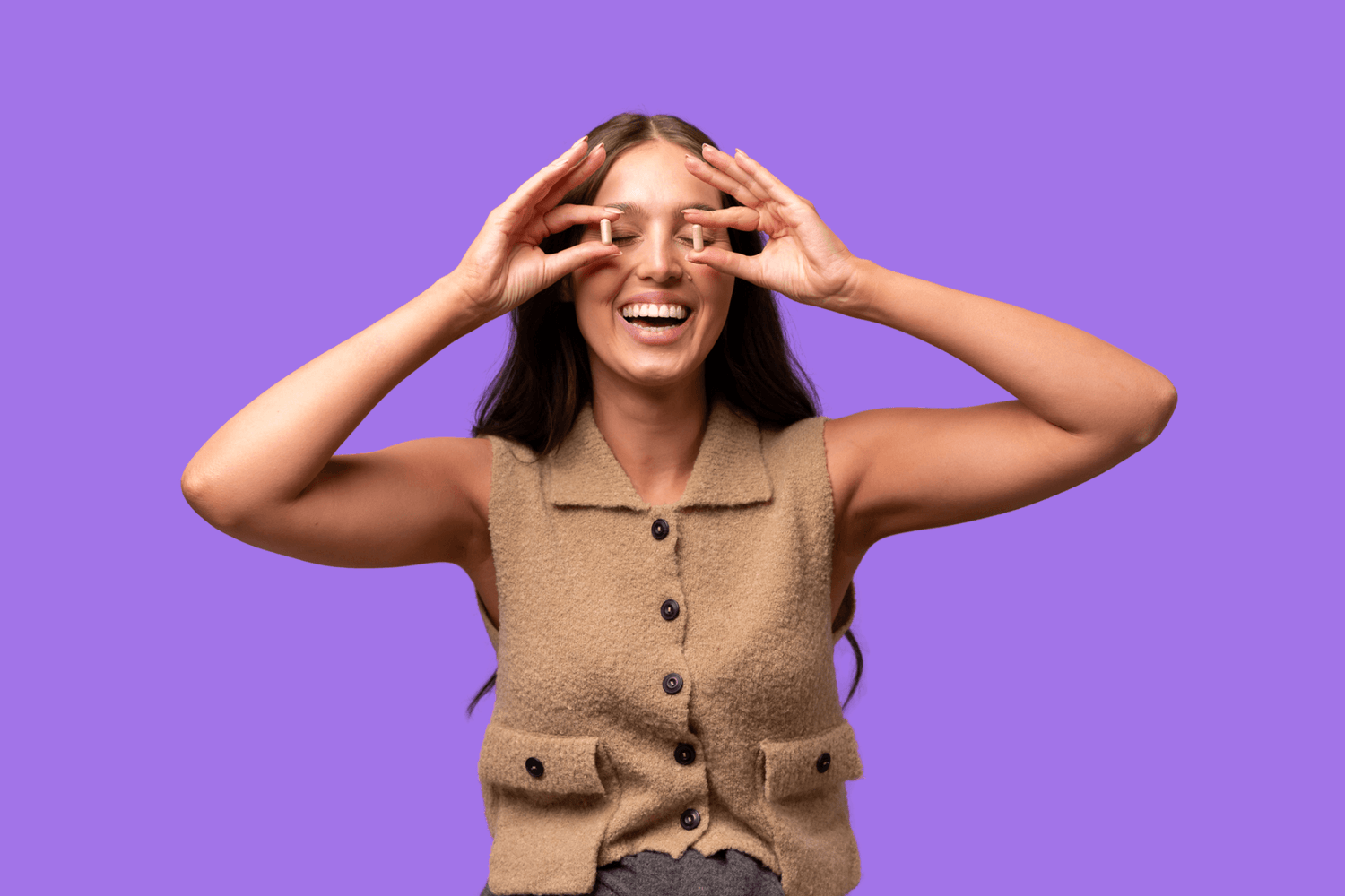 Woman wearing a brown vest against a purple background holds a YAAY More Than Fibre Capsule up to each eye